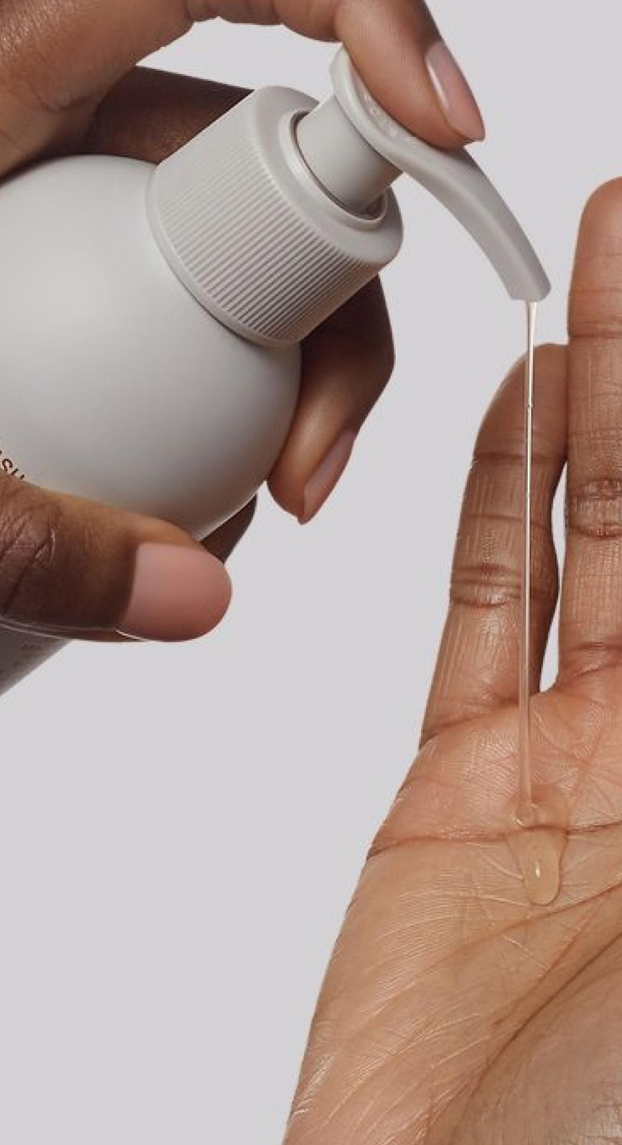Nerra body wash being dispensed onto a hand against a neutral background